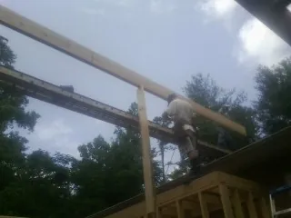 Carpenter setting a ridge beam over a new addition frame — Ice Dam Removal by Roofing Brothers in Supply