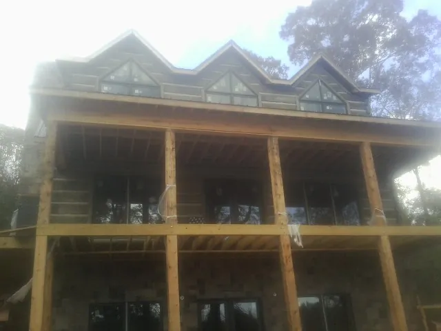 Dormers and porch framing on a large log home under construction — Roof Coating work by our crew in Supply