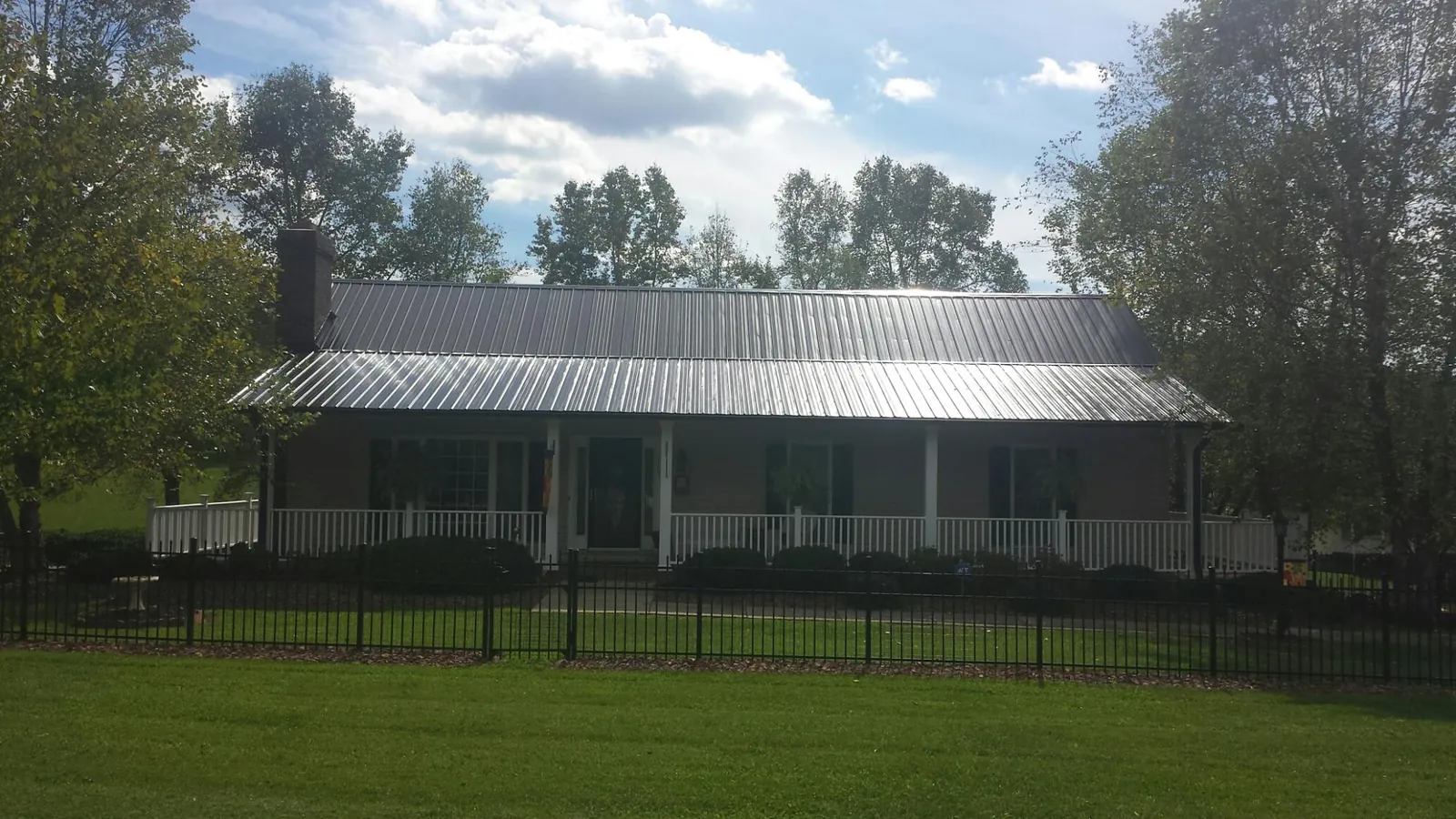 Gray metal roof on a brick ranch with a full width front porch — Gutter Guard Installation work by our crew in Supply