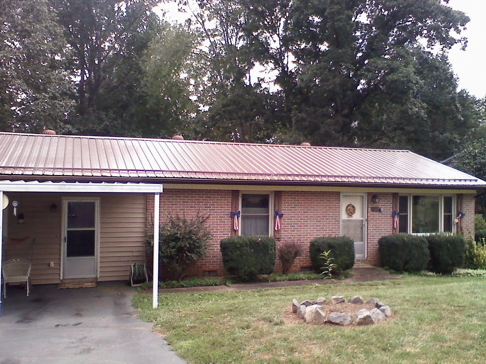 Bronze metal roof and carport on a brick ranch home — Roof Repair work by our crew in Supply